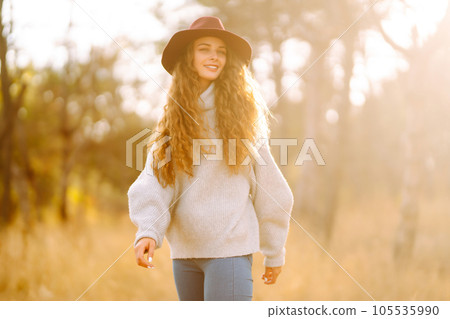 Stylish woman in sweater and hat enjoys autumn nature. People, freedom, lifestyle, travel concept. Stylish woman in sweater and hat enjoys autumn nature. People, freedom, lifestyle, travel concept. 105535990