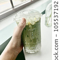 hand putting green peas into glass matcha latte  105537192