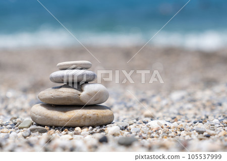 Round stones lie on top of each other in a column on the seashore on a sunny summer day. The concept of order and tranquility 105537999