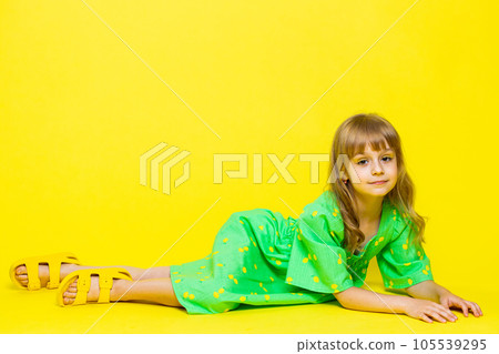 Girl child kid in green dress lying on floor, relaxing, chill enjoying, looking at camera with smile 105539295