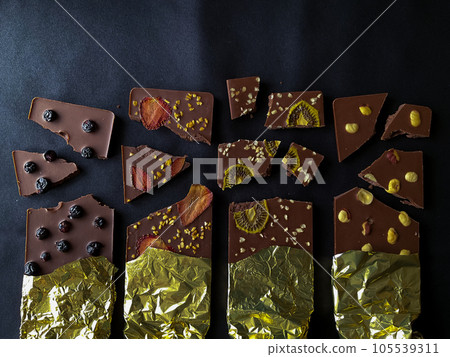 Pieces of chocolate. With berries, strawberries, kiwi and nuts in gold foil. 105539311