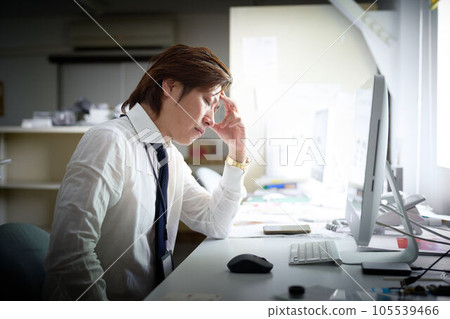 年輕的商人坐在辦公桌前,抱著頭 年輕的商人坐在辦公桌前,抱著頭 105539466