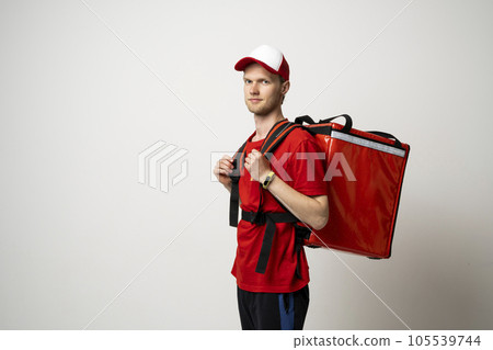 Delivery employee man in red uniform with athermal food bag backpack work as a courier. Delivery employee man in red uniform with athermal food bag backpack work as a courier. 105539744