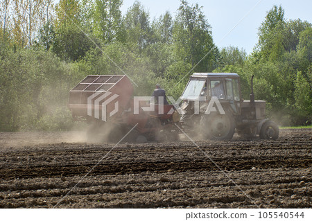 Potato planter works in farmers field as tractor trailer. Potato planter works in farmers field as tractor trailer. 105540544