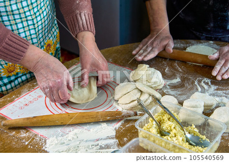 Cooking homemade pies with filling in rural house, rolling out dough, forming pie. Cooking homemade pies with filling in rural house, rolling out dough, forming pie. 105540569
