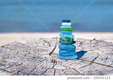 Balanced pyramid of glass bottle shards polished by sea On wooden surface by sea. Zen pyramid for meditation Balanced pyramid of glass bottle shards polished by sea On wooden surface by sea. Zen pyramid for meditation 105541123