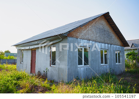 An abandoned unfinished house on a grassy plot.  105541197
