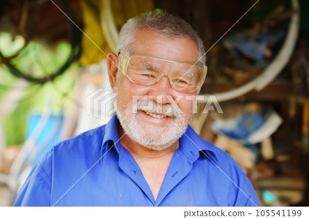 an elderly man in goggles to work with a circular saw an elderly man in goggles to work with a circular saw 105541199