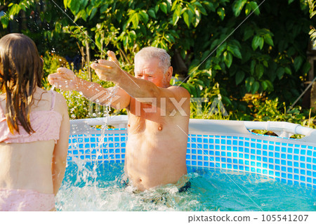 Grandpa and granddaughter play and have fun in the pool. Grandpa and granddaughter play and have fun in the pool. 105541207