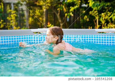 Cute teenage girl in pink swimsuit playing in a small pool. Cute teenage girl in pink swimsuit playing in a small pool. 105541208