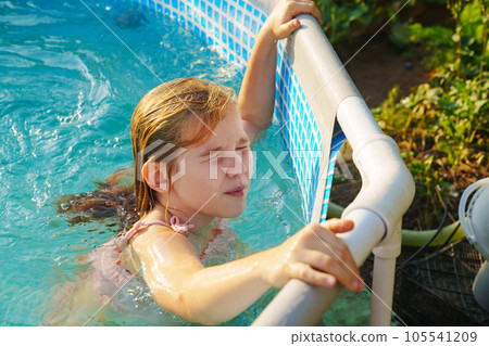 Cute teenage girl in pink swimsuit playing in a small pool. Cute teenage girl in pink swimsuit playing in a small pool. 105541209