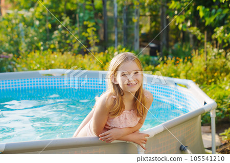 Cute teenage girl in pink swimsuit playing in a small pool. Cute teenage girl in pink swimsuit playing in a small pool. 105541210