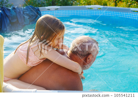 Grandpa and granddaughter play and have fun in the pool. Grandpa and granddaughter play and have fun in the pool. 105541211