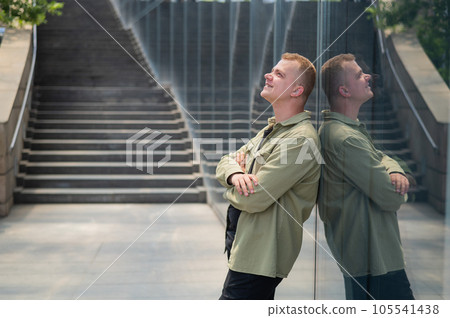 A pensive man stands against the backdrop of a skyscraper. 105541438