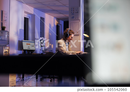 Positive manager dancing and having fun in startup office, enjoying listening music during work break. Businesswoman wearing headphone while working overtime at financial growth report Positive manager dancing and having fun in startup office, enjoying listening music during work break. Businesswoman wearing headphone while working overtime at financial growth report 105542060