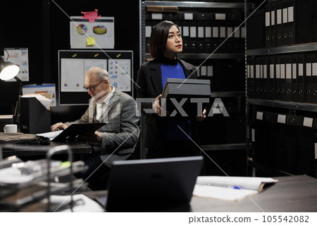 Professional asian bookkeeper storing bureaucratic accounting analytical data paperwork boxes in cabinet room office. Professional businesswoman in file storage administration workplace 105542082