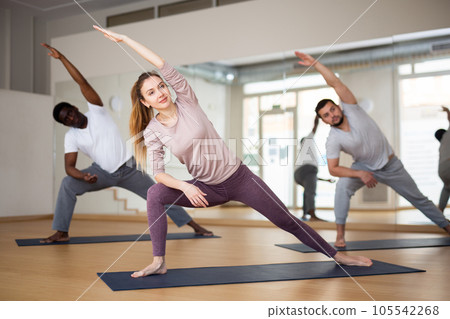 Woman doing Utthita Parsvakonasana during group yoga workout Woman doing Utthita Parsvakonasana during group yoga workout 105542268
