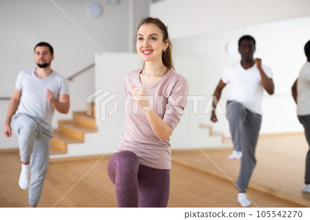 Woman dancing aerobic dance with men in studio Woman dancing aerobic dance with men in studio 105542270