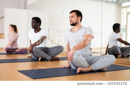 Man exercising lotus pose with group Man exercising lotus pose with group 105542278