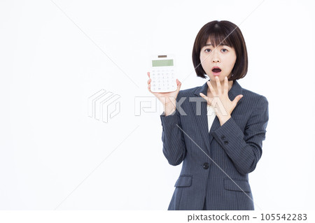 驚訝的三十多歲的女人在白色背景前拿著計算器 驚訝的三十多歲的女人在白色背景前拿著計算器 105542283