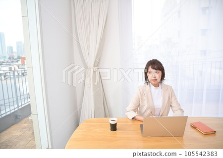 Young woman working on laptop at desk indoors Young woman working on laptop at desk indoors 105542383