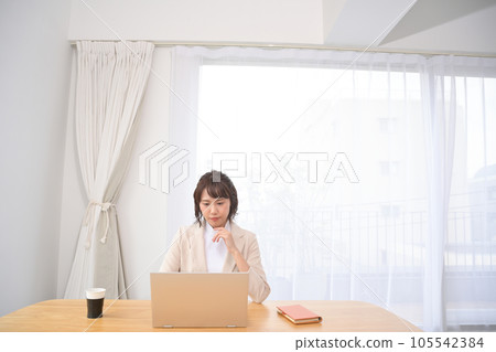Woman looking at laptop at table indoors Woman looking at laptop at table indoors 105542384