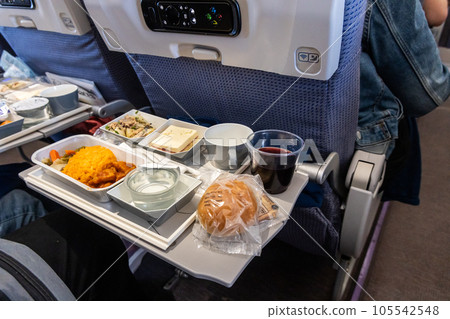 Inflight airplane Asian food set meal served consisting rice and spicy chicken, appetizer, dessert, bun and red wine Inflight airplane Asian food set meal served consisting rice and spicy chicken, appetizer, dessert, bun and red wine 105542548