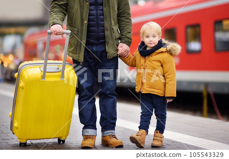 Smiling little boy and his father waiting express train on railway station platform Smiling little boy and his father waiting express train on railway station platform 105543329