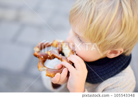 Little tourist eating traditional bavarian bread called pretzel Little tourist eating traditional bavarian bread called pretzel 105543348