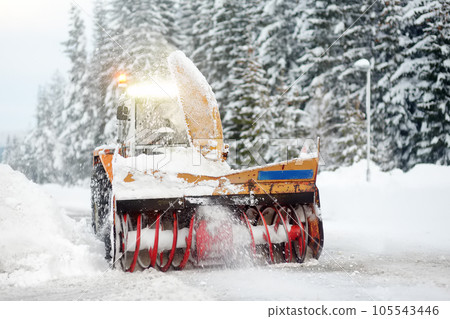 A snowplow truck clearing a snow-covered road in the European Alps while a snowstorm. Drifts and snow drifts during a snowfall. A snowplow truck clearing a snow-covered road in the European Alps while a snowstorm. Drifts and snow drifts during a snowfall. 105543446