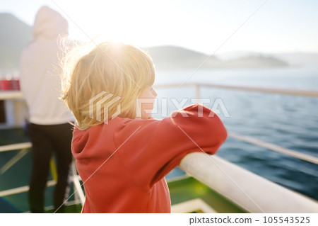Blond little child is traveling with family by ferry or ship. Schoolboy is admiring the landscape of the Adriatic Sea. Cruise during the holidays. 105543525