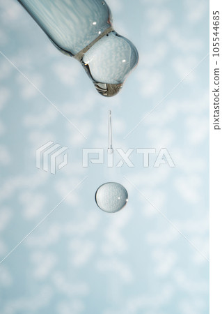 A dripping pipette with a drop of cosmetics gel. A dripping pipette with a drop of cosmetics gel. 105544685
