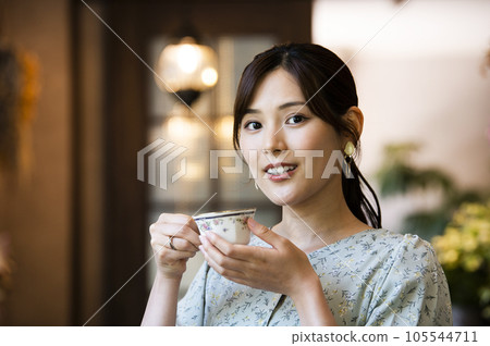 一位年輕女子在咖啡館喝咖啡，看著鏡頭 105544711