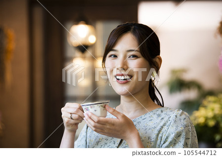 A young woman drinking coffee at a cafe looking at the camera A young woman drinking coffee at a cafe looking at the camera 105544712