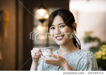 A young woman drinking coffee at a cafe looking at the camera A young woman drinking coffee at a cafe looking at the camera 105544713
