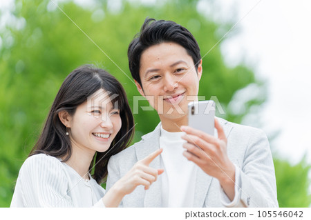 一對夫婦在戶外看智能手機 一對夫婦在戶外看智能手機 105546042