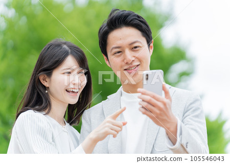 一對夫婦在戶外看智能手機 105546043