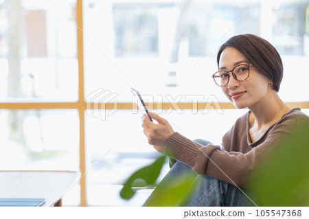 A woman sitting on a sofa and relaxing A woman sitting on a sofa and relaxing 105547368