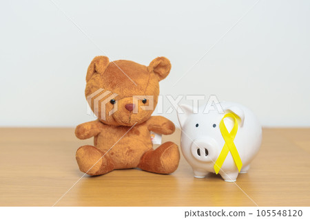 International Childhood Cancer Awareness month, Children toy with golden yellow color Ribbon with Piggy Bank for Donation, Charity, Campaign, Money Saving, Fund and World cancer day concept International Childhood Cancer Awareness month, Children toy with golden yellow color Ribbon with Piggy Bank for Donation, Charity, Campaign, Money Saving, Fund and World cancer day concept 105548120