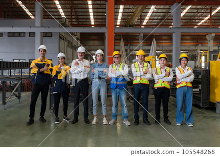 Industrial teamwork. Professionals donning safety hard hats standing together in a bustling factory. Industrial teamwork. Professionals donning safety hard hats standing together in a bustling factory. 105548268