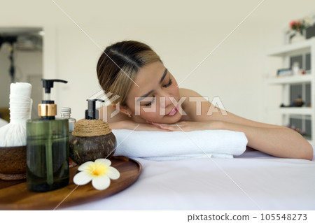 Holistic luxury wellness experience. A serene woman reclining leisurely within a soothing spa ambiance, surrounded by elements promoting tranquility. 105548273