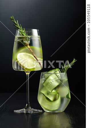Gin tonic with ice, rosemary, lime, and cucumber in frosted glasses. 105549118
