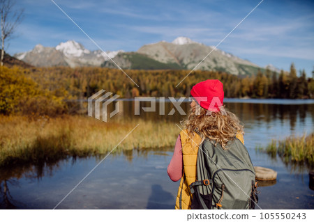 Rear view of woman standing on the shore of the lake in mountains. Rear view of woman standing on the shore of the lake in mountains. 105550243