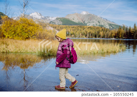 Little girl walking in the shore of lake, in the middle of beautiful autumn nature. Little girl walking in the shore of lake, in the middle of beautiful autumn nature. 105550245