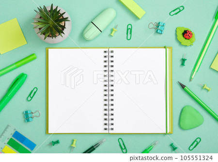 Open notebook with green pen, pencil and marker on pastel green background 105551324