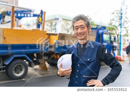 A craftsman standing in front of a construction site with a smile 105553912