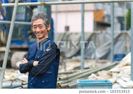 A craftsman standing in front of a construction site with a smile 105553915