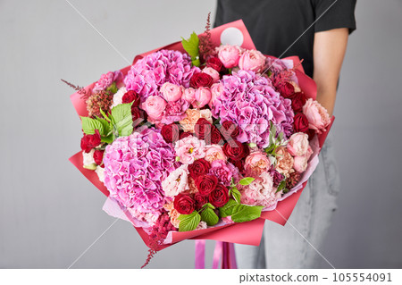 Small Beautiful bouquet of mixed flowers in woman hand. Floral shop concept . Beautiful fresh cut bouquet. Flowers delivery 105554091