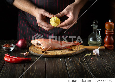 The chef adds fresh lemon juice to raw Sebastes fish. The concept of a delicious red fish lunch for a restaurant or hotel. The chef adds fresh lemon juice to raw Sebastes fish. The concept of a delicious red fish lunch for a restaurant or hotel. 105554470