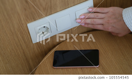 Hand light switch in woman wall and smartphone closeup Hand light switch in woman wall and smartphone closeup 105554545